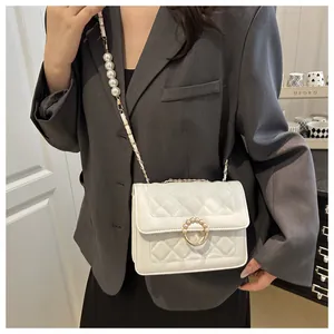 Gros plan sur le sac matelassé blanc avec ornements de perles et bandoulière dorée