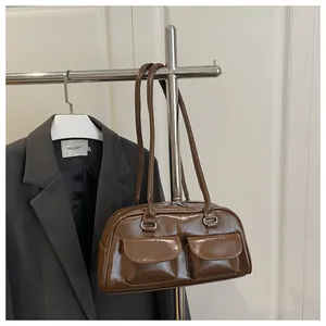 Detail of brown glossy leather bag with double front flap pockets and silver hardware