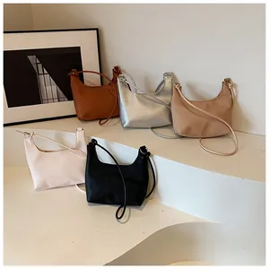 Detalle de bolsos de media luna en cuero negro, plateado, marrón, beige y blanco crema