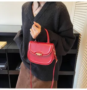 Gros plan d'un sac besace en cuir rouge vif avec un fermoir cylindrique doré élégant