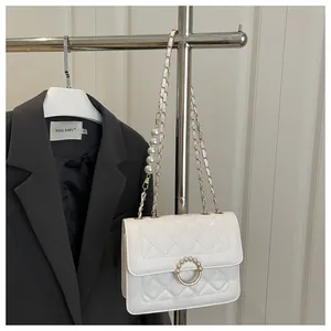Détail du sac bandoulière matelassé blanc avec boucle perle et chaîne élégante