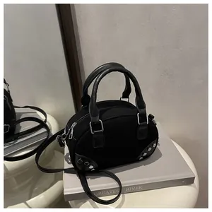 Dettaglio della borsa bowling nera con rivetti argentati e texture in tela e pelle