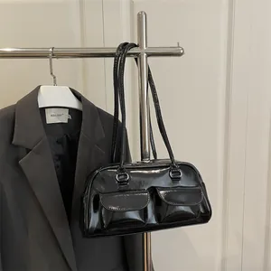 Minimalist black patent leather shoulder bag with dual front pockets and glossy finish