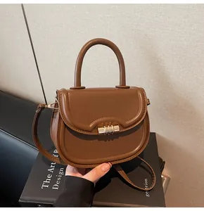 Détail du sac selle marron avec fermoir métallique doré et poignée supérieure