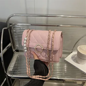 Sac à bandoulière rose matelassé avec boucle en perle et breloque en perles