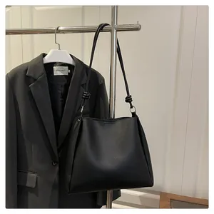 Detail of black tote bag shoulder strap with decorative knot and silver metal ring