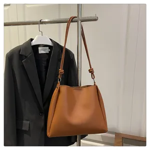 Detail showing the thin knotted shoulder strap and smooth leather texture of the brown tote
