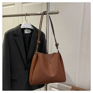 Close-up of vintage brown leather tote bag with elegant knot handle detail on a hanger