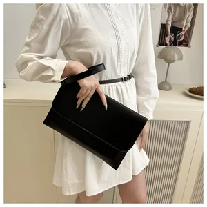 Dettaglio di una pochette a busta minimalista in pelle nera in un ambiente elegante