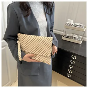 Elegante pochette a busta con stampa monogram e cinturino da polso rimovibile tenuta dal modello