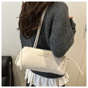 Macro detail of creamy white leather shoulder bag with side drawstring bow decoration