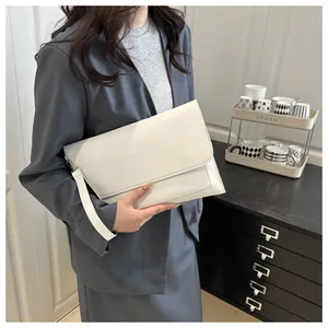 Dettaglio di una pochette a busta in pelle bianca con cinturino da polso da un modello