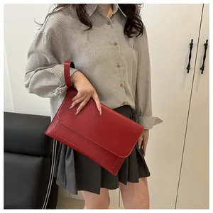 Pochette a busta in pelle rosso intenso tenuta da modella con gonna a pieghe