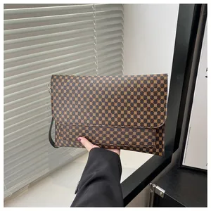 Pochette a busta piatta con motivo geometrico marrone tenuta da persona in abito