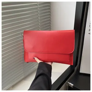 Vista dettagliata di una pochette rossa in finta pelle con cuciture fini e anello metallico