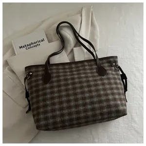 Détail du sac seau en tweed avec bandoulière posé sur un blazer blanc et un livre