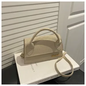 Detail of beige suede crossbody bag with gold logo on white shutters background