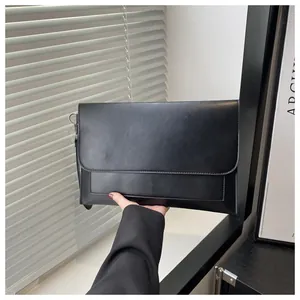 Dettaglio della pochette a busta nera opaca con cuciture fini e anello in metallo
