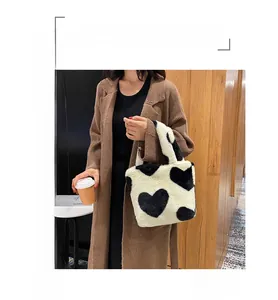 Detail of plush bucket bag with heart patterns held by model in stylish winter coat