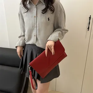 Elegante borsa a bustina in pelle rossa con cinturino rimovibile indossata da una modella