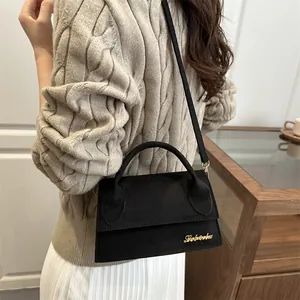 Minimalist black matte leather crossbody bag with gold logo on a lifestyle model