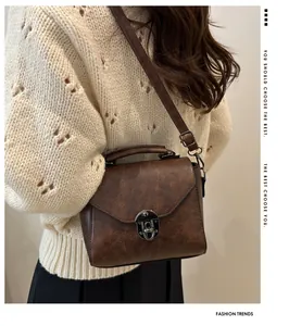 Detail van bruine retro crossbody tas met litchi-textuur en vintage metalen sluiting