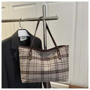 Détail du sac cabas vintage en laine à carreaux avec lanières en cuir marron et rivets