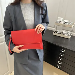 Elegante borsa a busta rossa in pelle lucida tenuta da una modella in contesto professionale