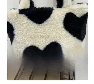 Close-up of fluffy black and white plush bucket bag with large heart pattern and soft texture