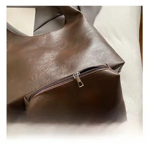 Detail of silver zipper and embossed logo on dark brown leather tote bag