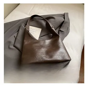 Detailed texture of dark brown leather hobo bag on a grey suiting fabric background