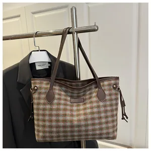 Détail du sac seau en tweed à motif à carreaux orange et vert et cordons en cuir