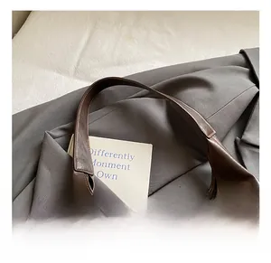 Detail of wide shoulder strap and premium leather texture on vintage brown tote bag