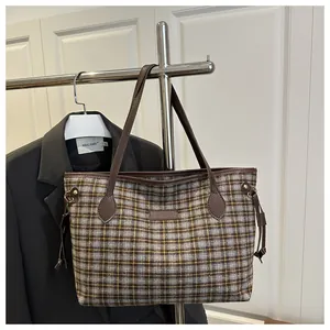 Détail du sac fourre-tout à carreaux avec poignées en cuir marron et détails de cordon