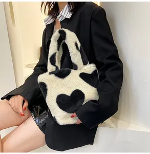 Detail of plush faux fur bucket bag with black heart patterns and soft wide handle