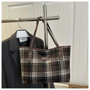 Détail du sac cabas en laine à carreaux avec lanières en cuir marron et rivets métalliques