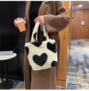Close-up of plush bucket bag with heart pattern held by a model in a winter coat