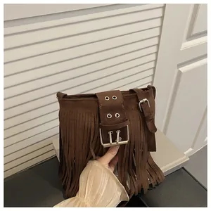 Détail du sac seau en daim marron foncé avec de longues franges et boucle métallique