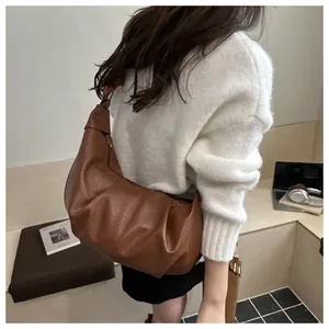 Detail view of brown pleated crescent bag featuring textured leather and knotted strap design