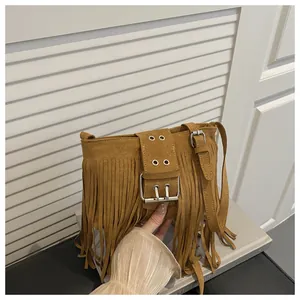 Gros plan détaillé du sac seau en daim gingembre avec franges et boucle argentée
