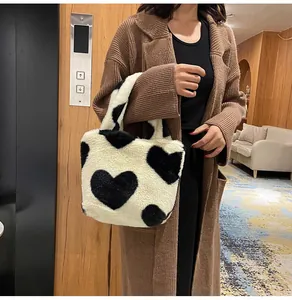 Close-up of plush bucket bag with black heart patterns and soft cream faux fur texture