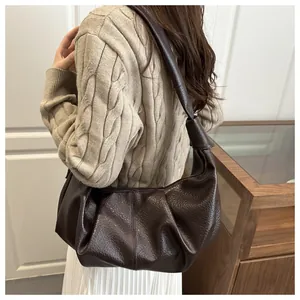 Detail of dark brown ruched dumpling bag with lychee texture leather and knotted strap