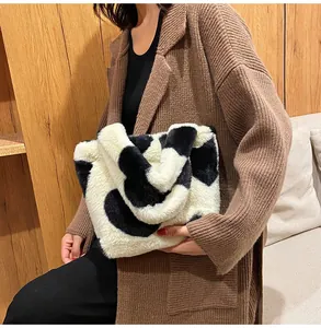 Fuzzy cow print bucket bag styled with a brown knit cardigan for a cozy winter look