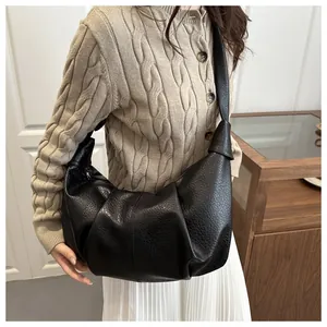 Close-up of black pleated hobo bag with litchi texture and knotted shoulder strap detail