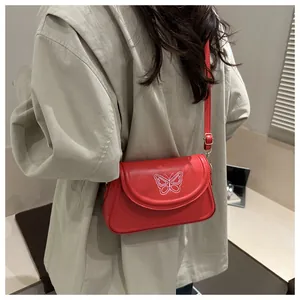 Detail of red shoulder bag with white butterfly embroidery and gold metal hardware