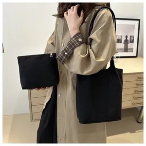 Dettaglio della borsa tote in pelle scamosciata nera e pochette coordinata sul modello