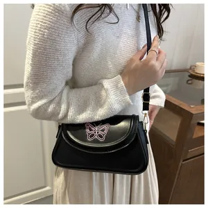 Detailed side view of a black small square crossbody bag with pink butterfly embroidery