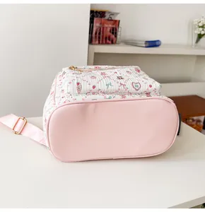Détail du sac à dos rose et blanc avec des motifs de fraises et d'oursons