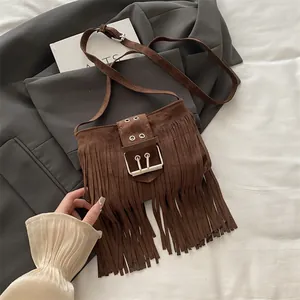 Vintage brown suede fringe crossbody bucket bag with large metal buckle on grey blazer