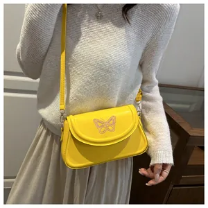 Détail d'un sac à bandoulière jaune vif avec broderie de papillon violet sur le rabat